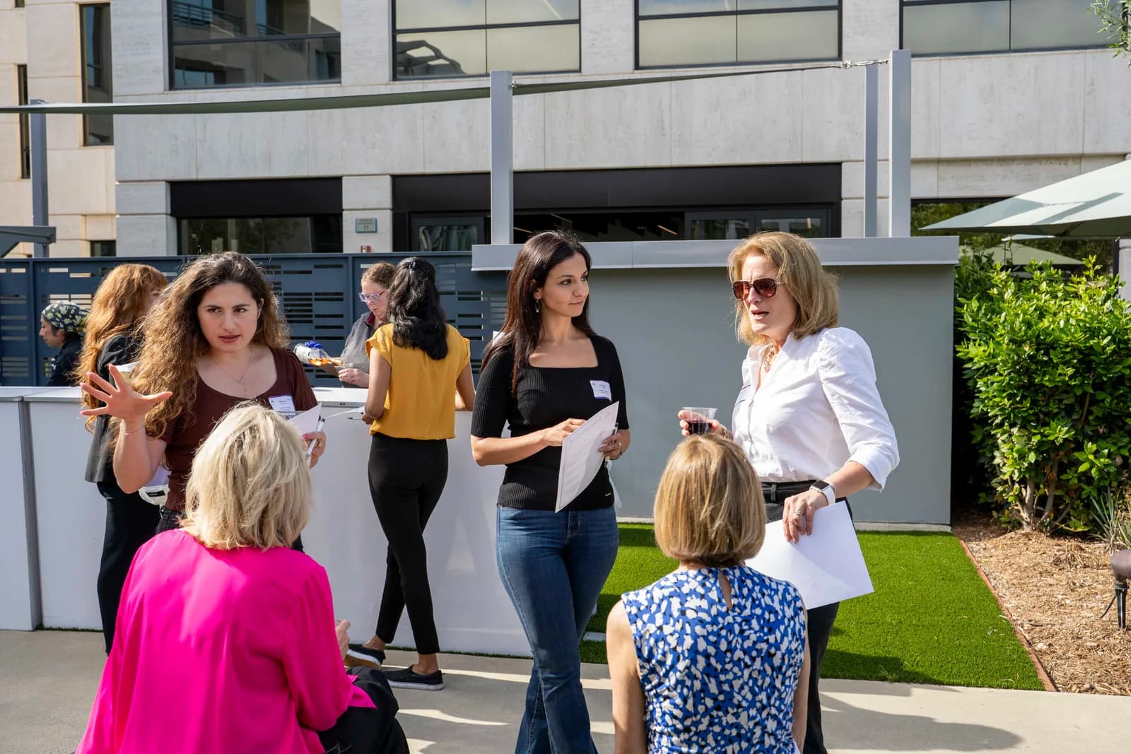 A circle of guests talking on the courtyard lawn at the 2025 Summer Wine Social